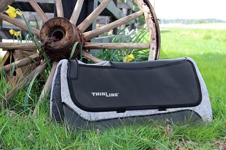 Square Pro-Tech Premium Felt Western Pad leaning up against a wagon wheel